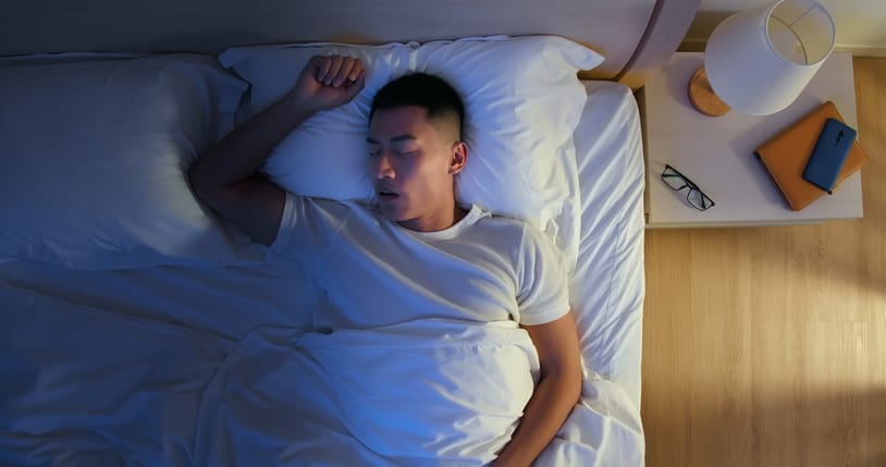 man sleeping on his back in bed