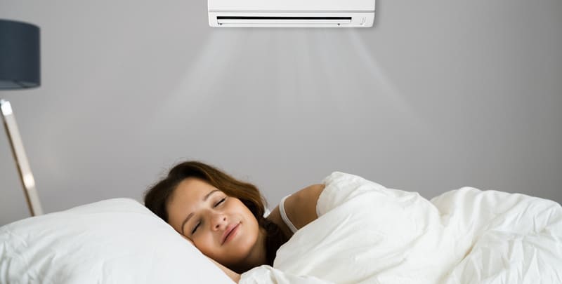 woman asleep in bed with air conditioner on